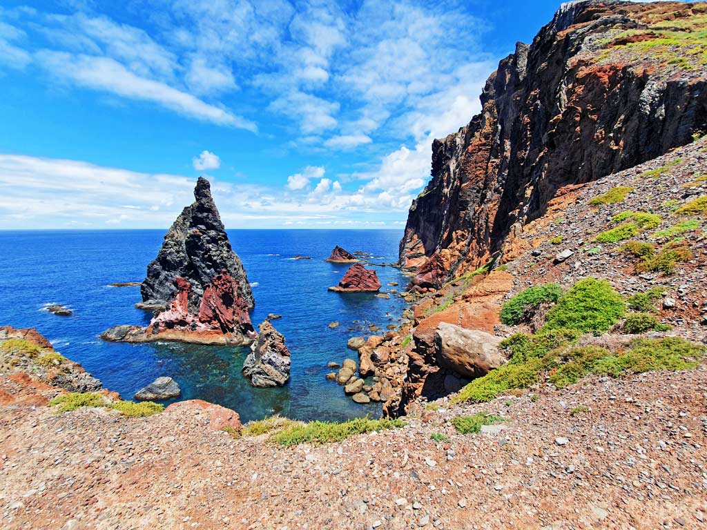Madeira wandern: Ausblick auf die erodierte Küste und rote Felsformationen im Meer