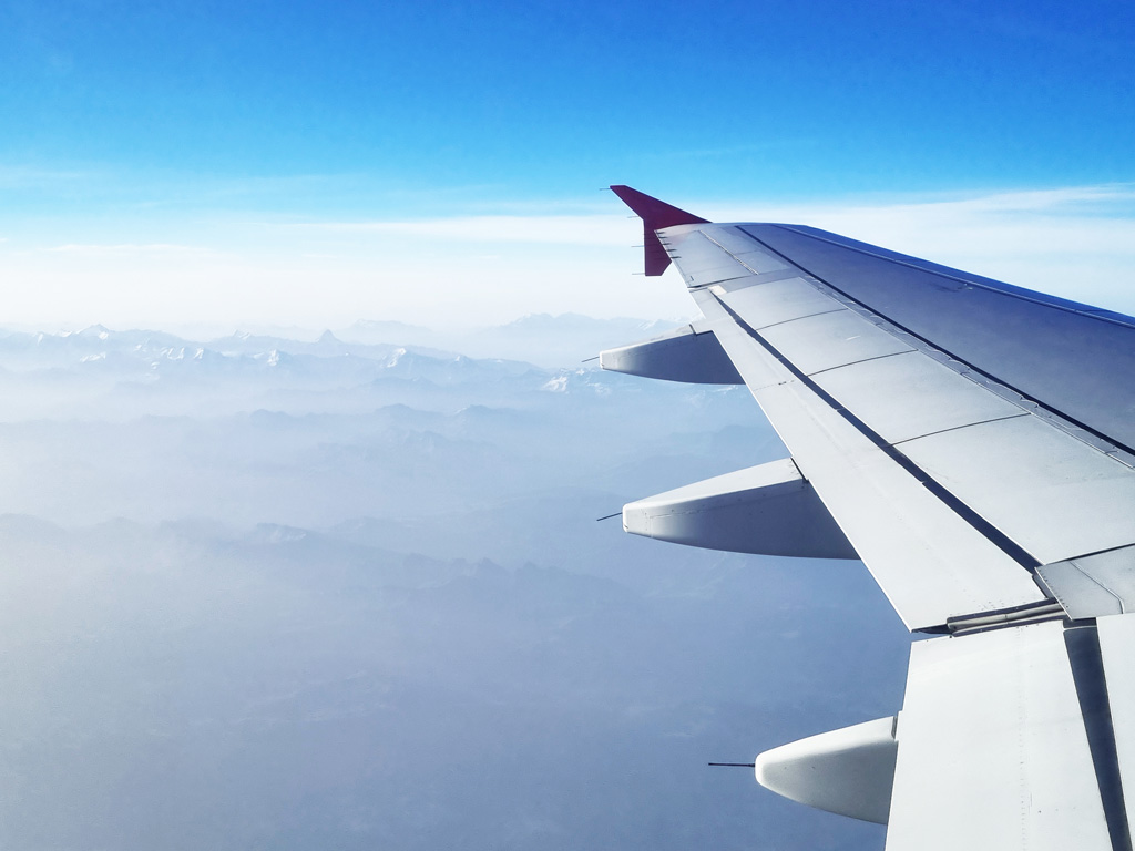 Tipps Anreise Zürich Flughafen: Blick aus dem Fenster eines Flugzeugs auf die Alpen beim Flug über die Schweiz