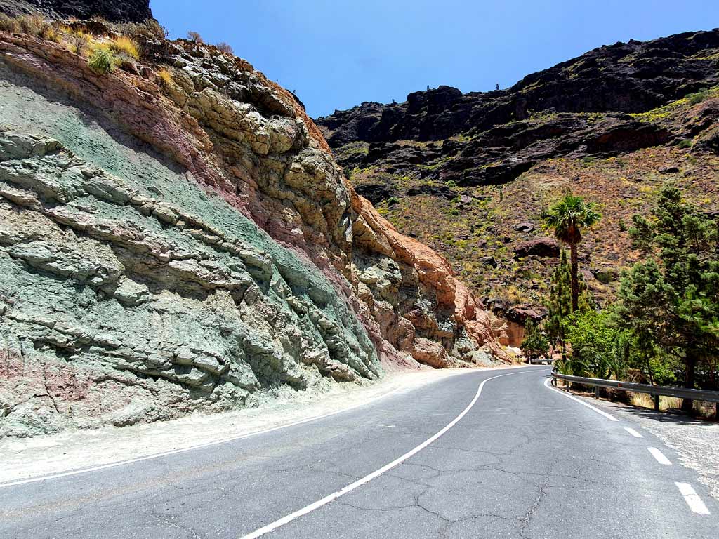 Auto mieten Gran Canaria: Strasse führt an farbenfrohen Felswänden vorbei