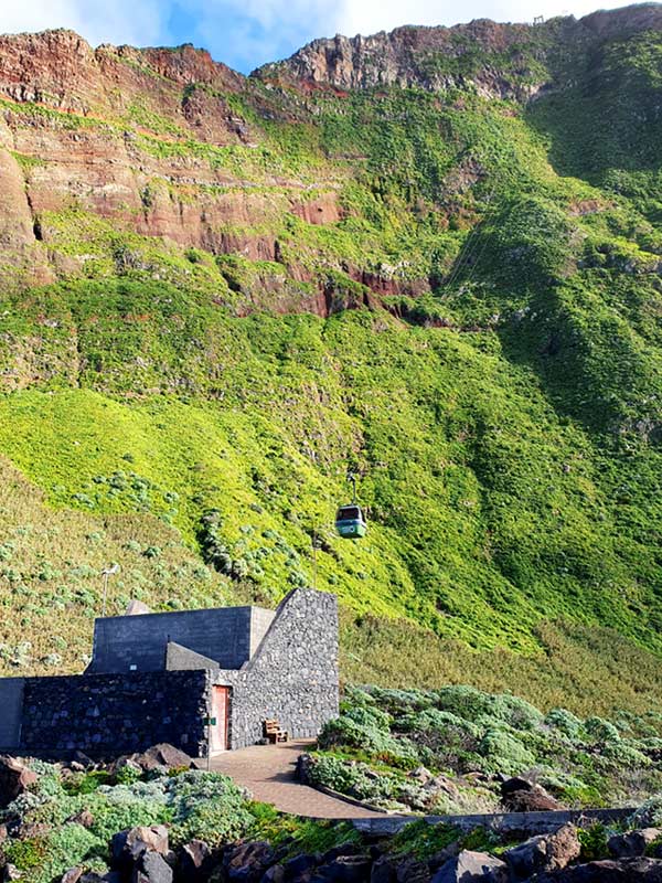 Achadas da Cruz Seilbahn: Die kleine grüne Gondel schwebt fast senkrecht vor der mächtigen Felswand hinunter zum Meer