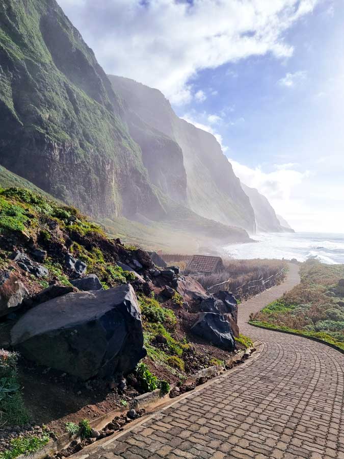 Küstenweg Achadas da Cruz mit den hohen, grün bewachsenen steilen Felswänden im Hintergrund.