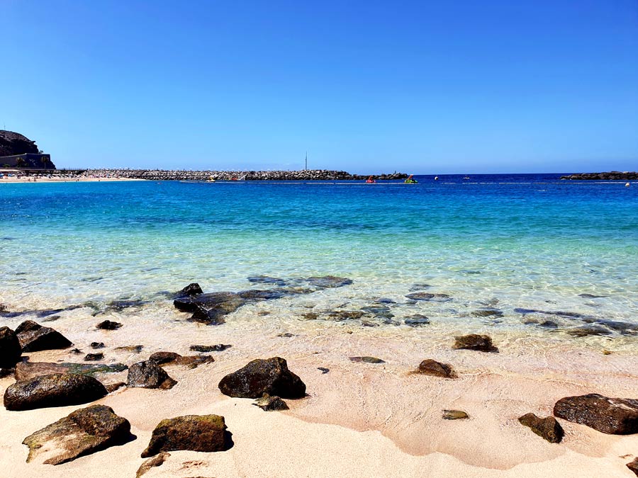 Glasklares Meerwasser und heller Sand an der Playa de Amadores auf Gran Canaria