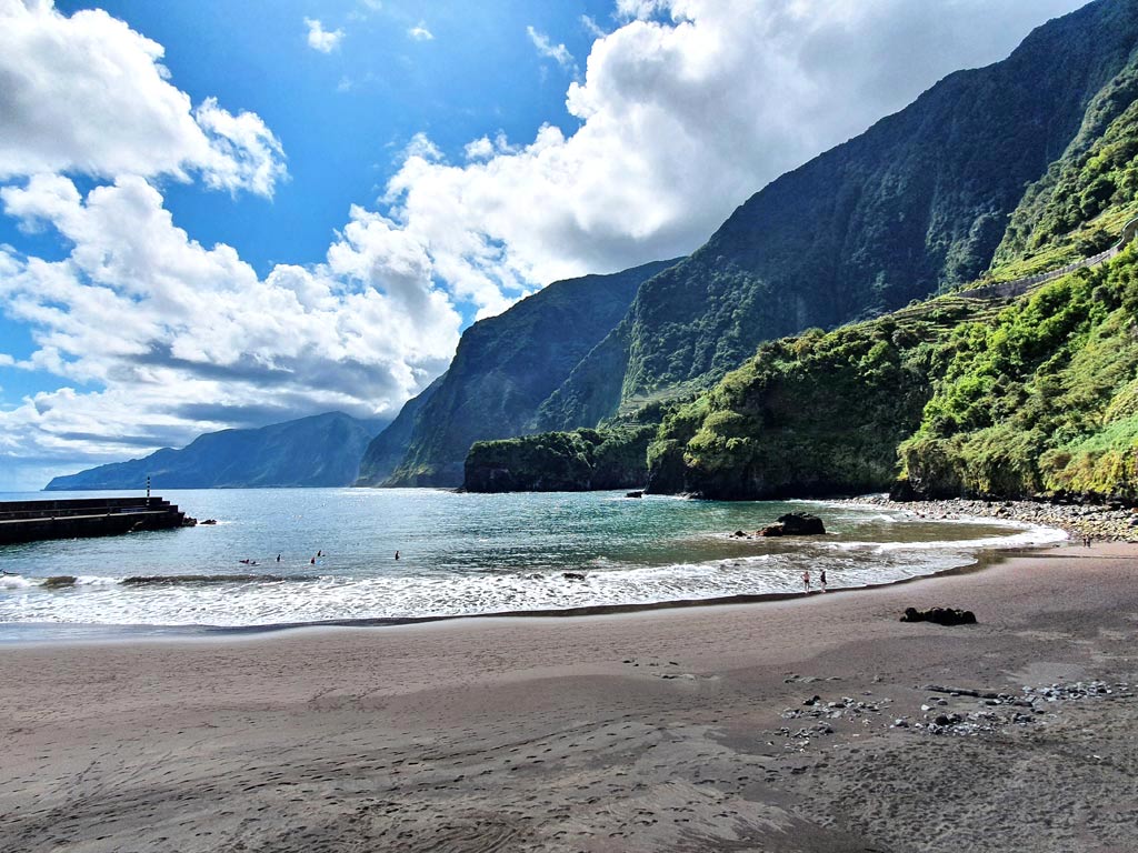 Porto Moniz Madeira Sehenswürdigkeiten: Schwarzer Strand in Seixal auf Madeira umgeben von mächtigen, grünen Steilklippen