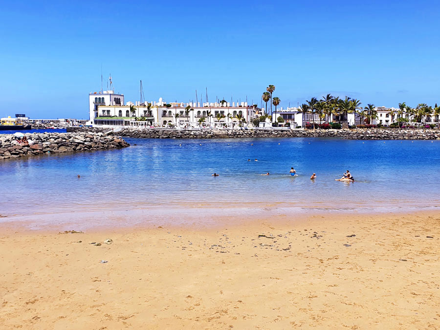 Gran Canaria schönste Orte: Heller Sandstrand Playa de Mogán mit Blick auf die weissen Häuser am Hafen Puerto de Mogán