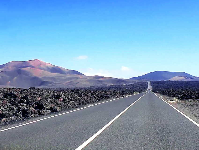 Lanzarote Mietwagen Tipps: Autofahren mit traumhaftem Ausblick auf die Feuerberge des Timanfaya Nationalparks, die sogenannten Montañas del Fuego.