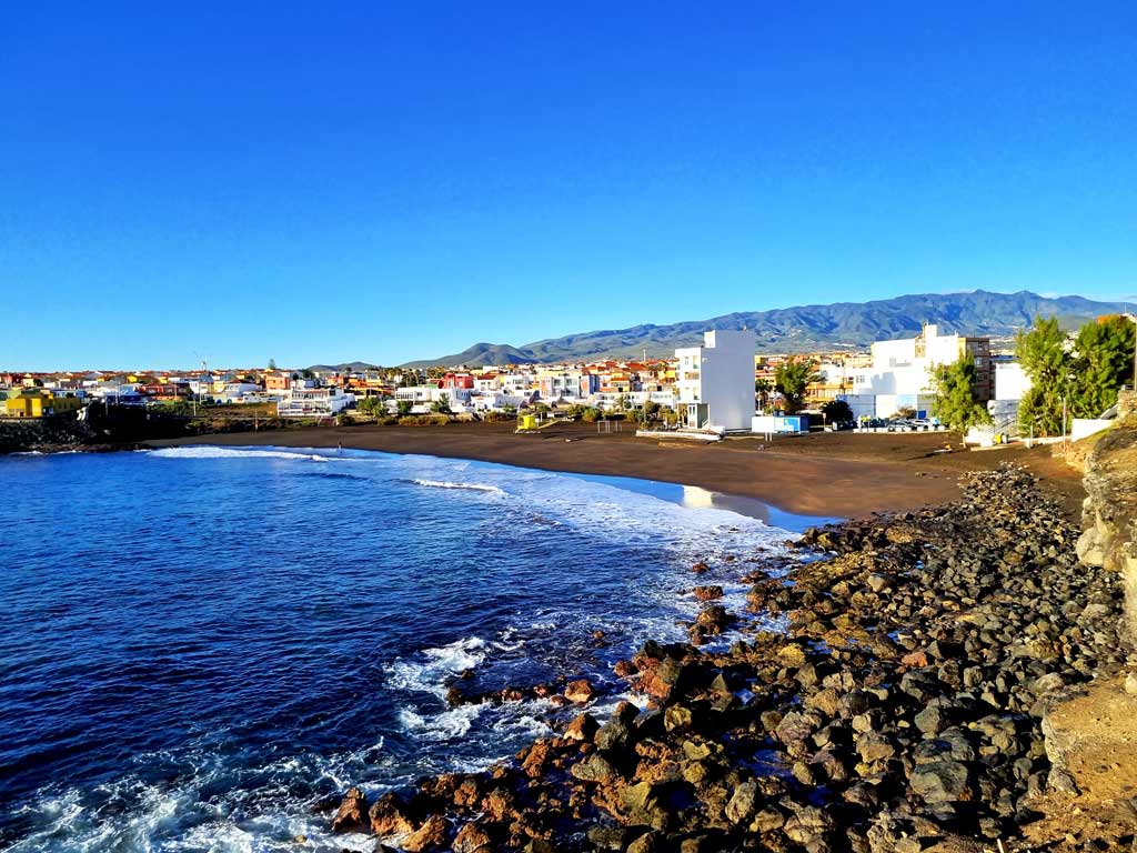 Gran Canaria wo übernachten: Bunte Häuserfassaden hinter dem dunklen Sandstrand Playa de La Garita weit weg vom Massentourismus auf Gran Canaria. Hier gibt es keine Gran Canaria Hotels.