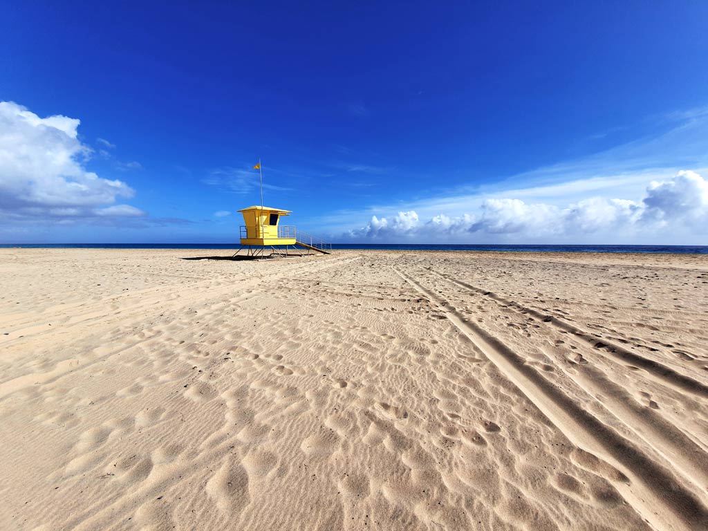 Fuerteventura Aktivitäten und Sehenswürdigkeiten - was tun auf Fuerteventura: Breiter, heller Sandstrand in Morro Jable mit gelbem Rettungsschwimmerhäuschen